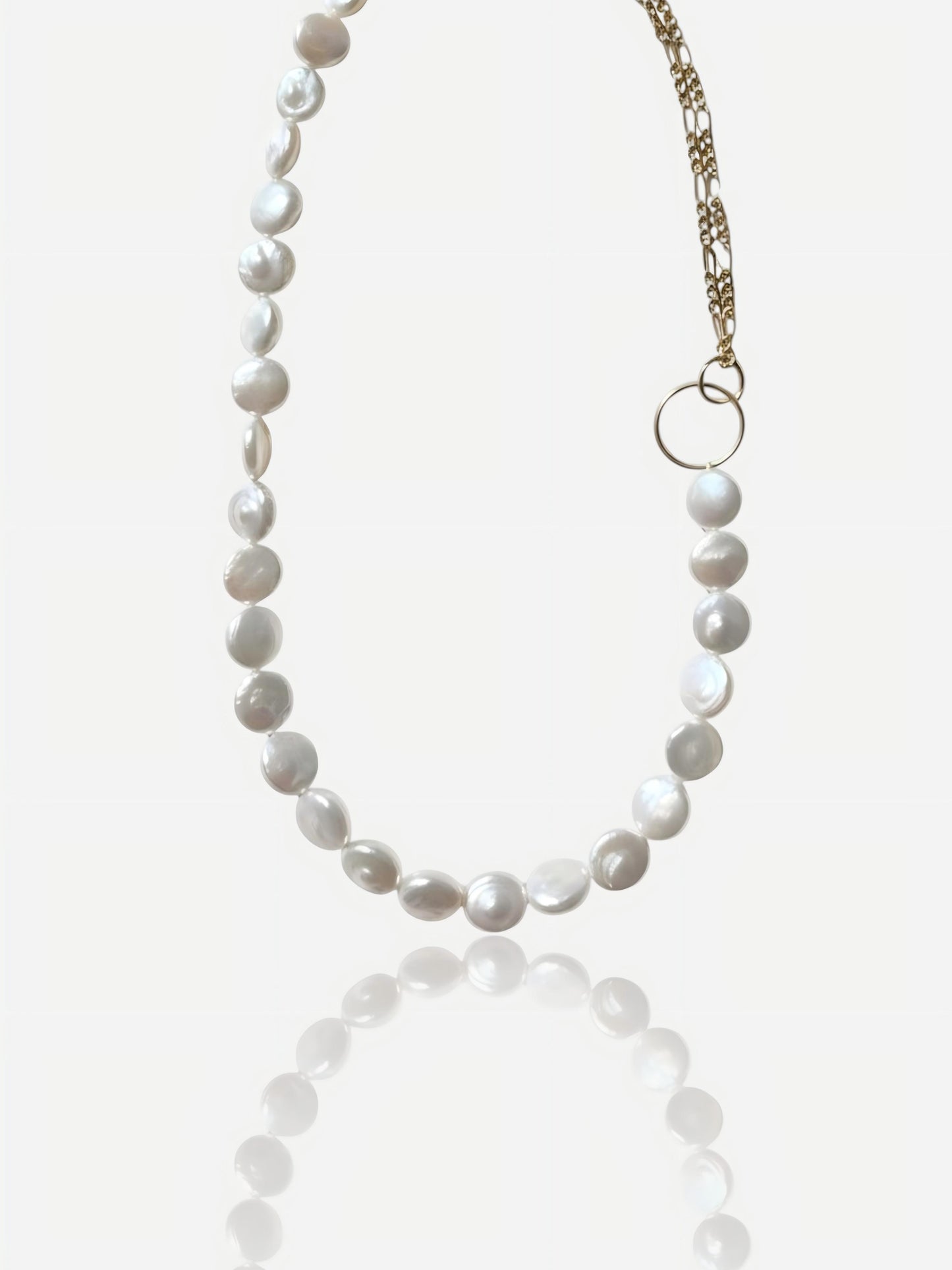 Close-up of Pearltide Eclipse necklace with half high-luster coin pearls and half 14K gold-filled chain connected by a gold ring on a white background, minimalist modernist jewelry.
