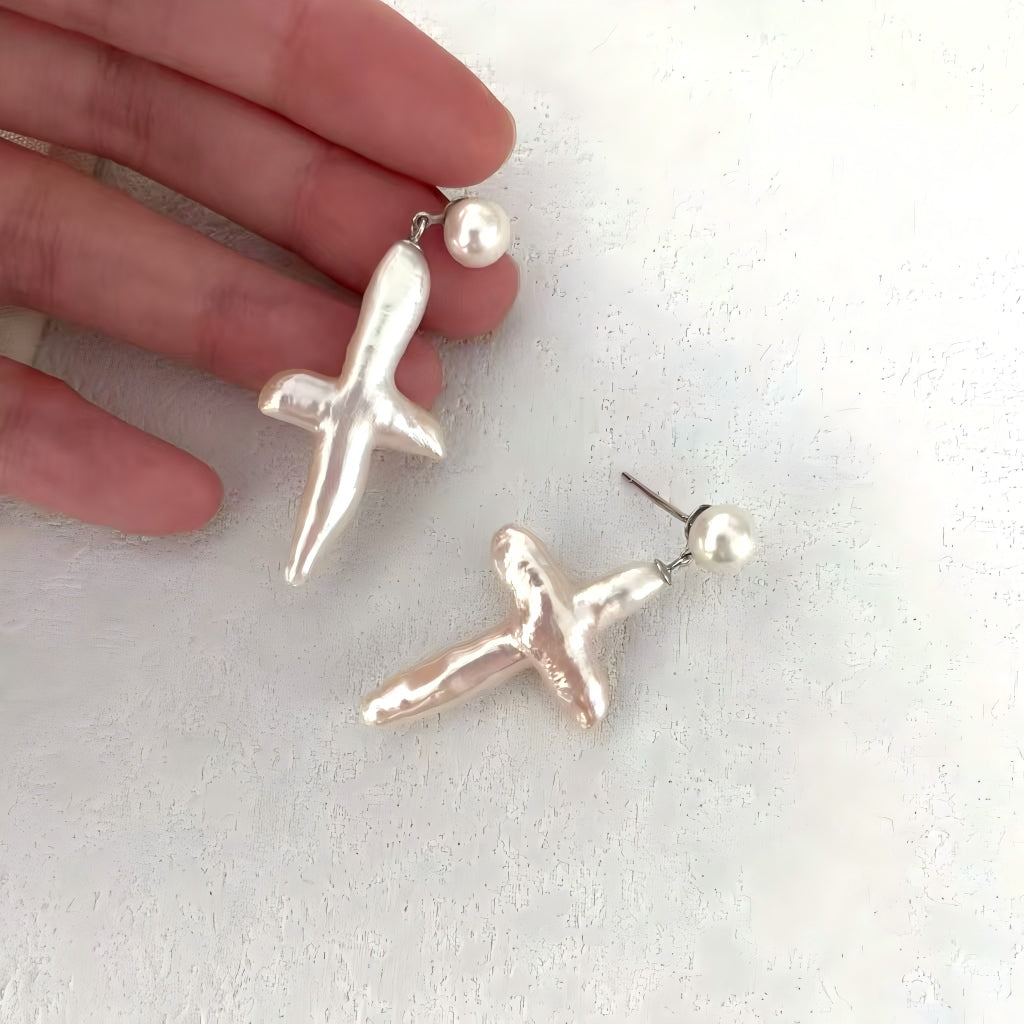 Close-up shot showing the irregular, natural texture and high luster of the cross-shaped freshwater pearl.