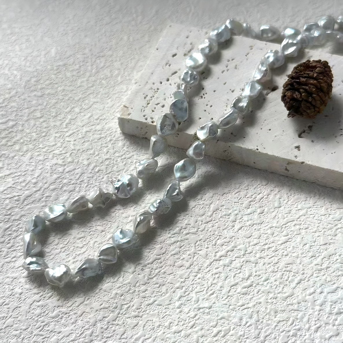 A stylish woman wearing the metallic silver-grey pearl necklace with a black top, highlighting the cool tones of the pearls.