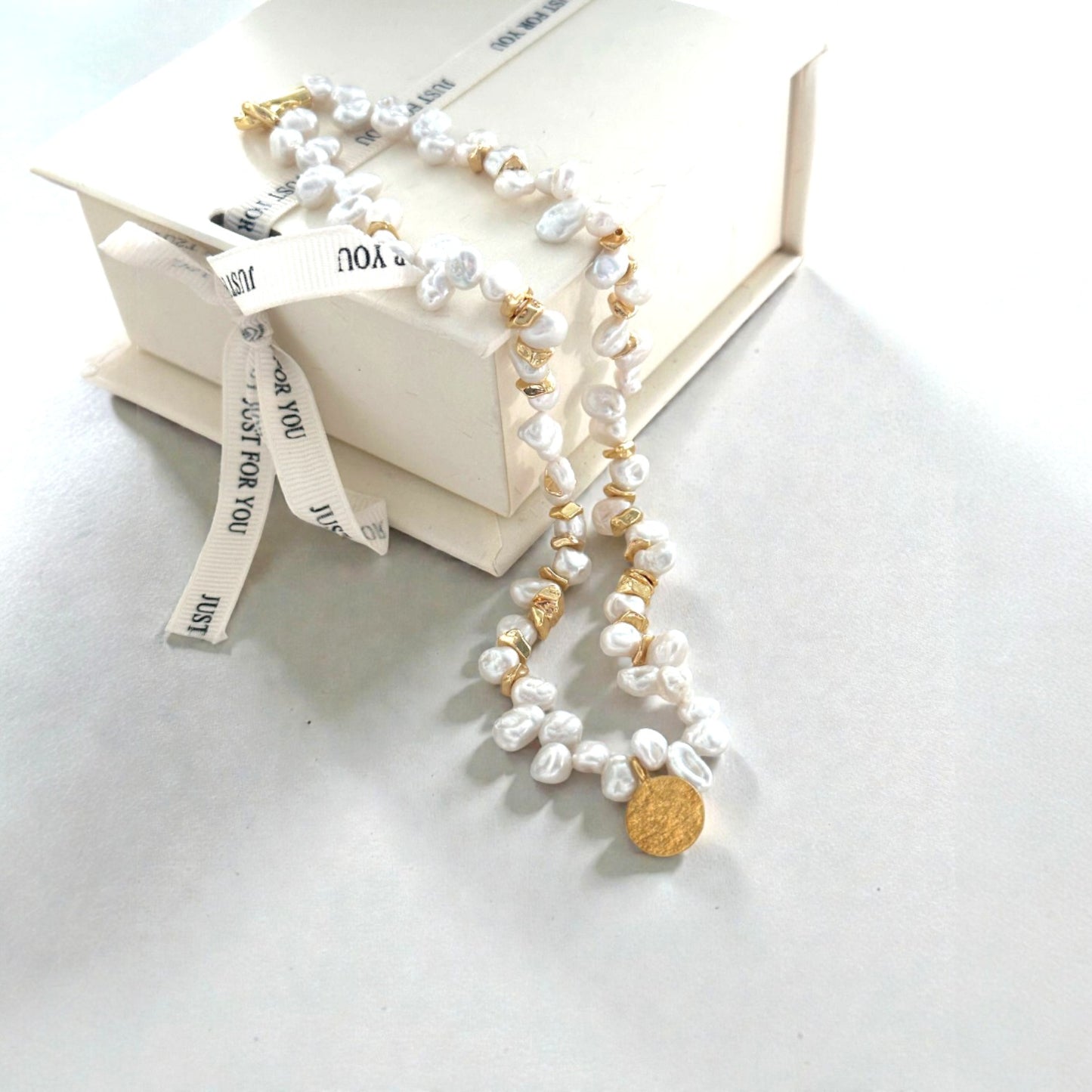 Golden Accents. Highlighting the hammered texture of the coin and the individual character of each baroque pearl.