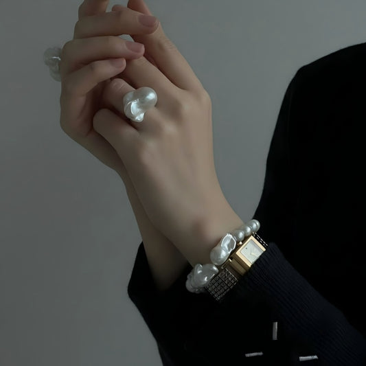 Woman's wrist wearing a chunky baroque pearl bracelet, styled with a neutral outfit to highlight the organic pearl textures and modern asymmetry.