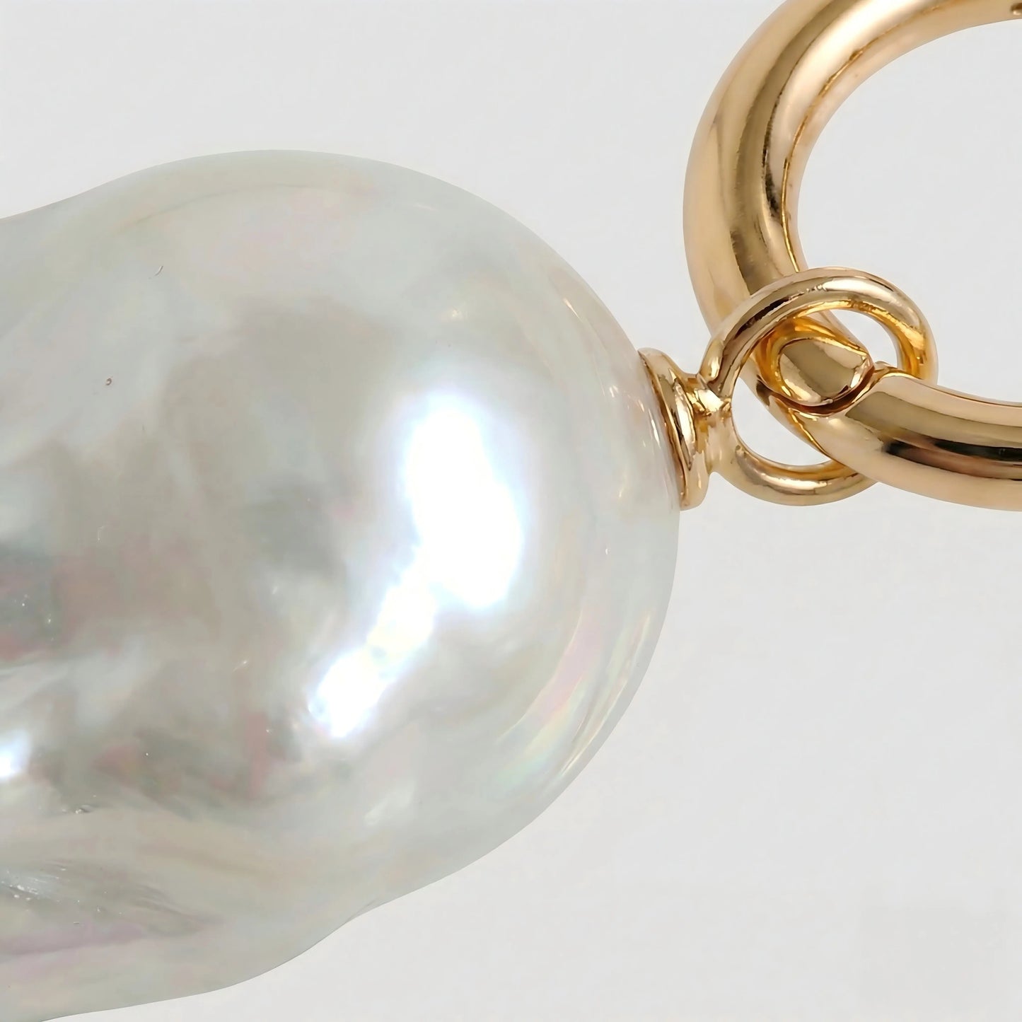 Close-up detail showing the unique organic texture of the natural baroque pearl and the smooth finish of the 18K gold plated setting.