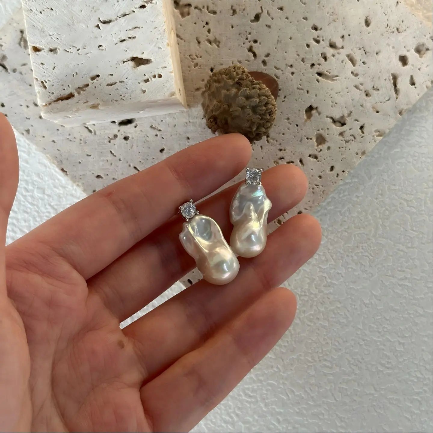 Close-up detail showing the high luster and organic texture of a white baroque pearl earring.