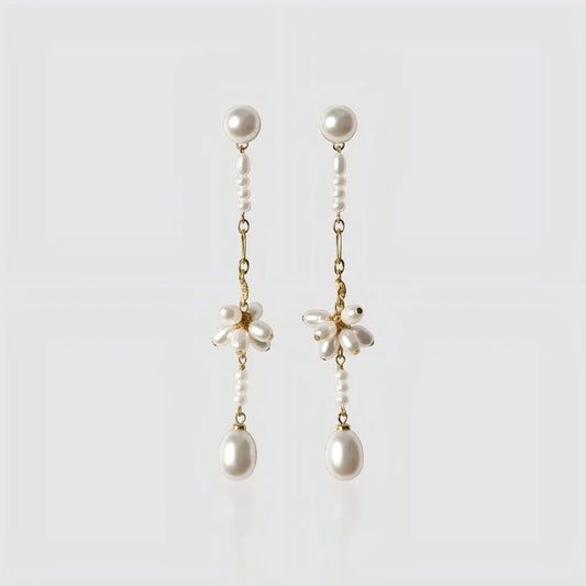 A pair of long gold-plated drop earrings by Pearltide against a plain white background.