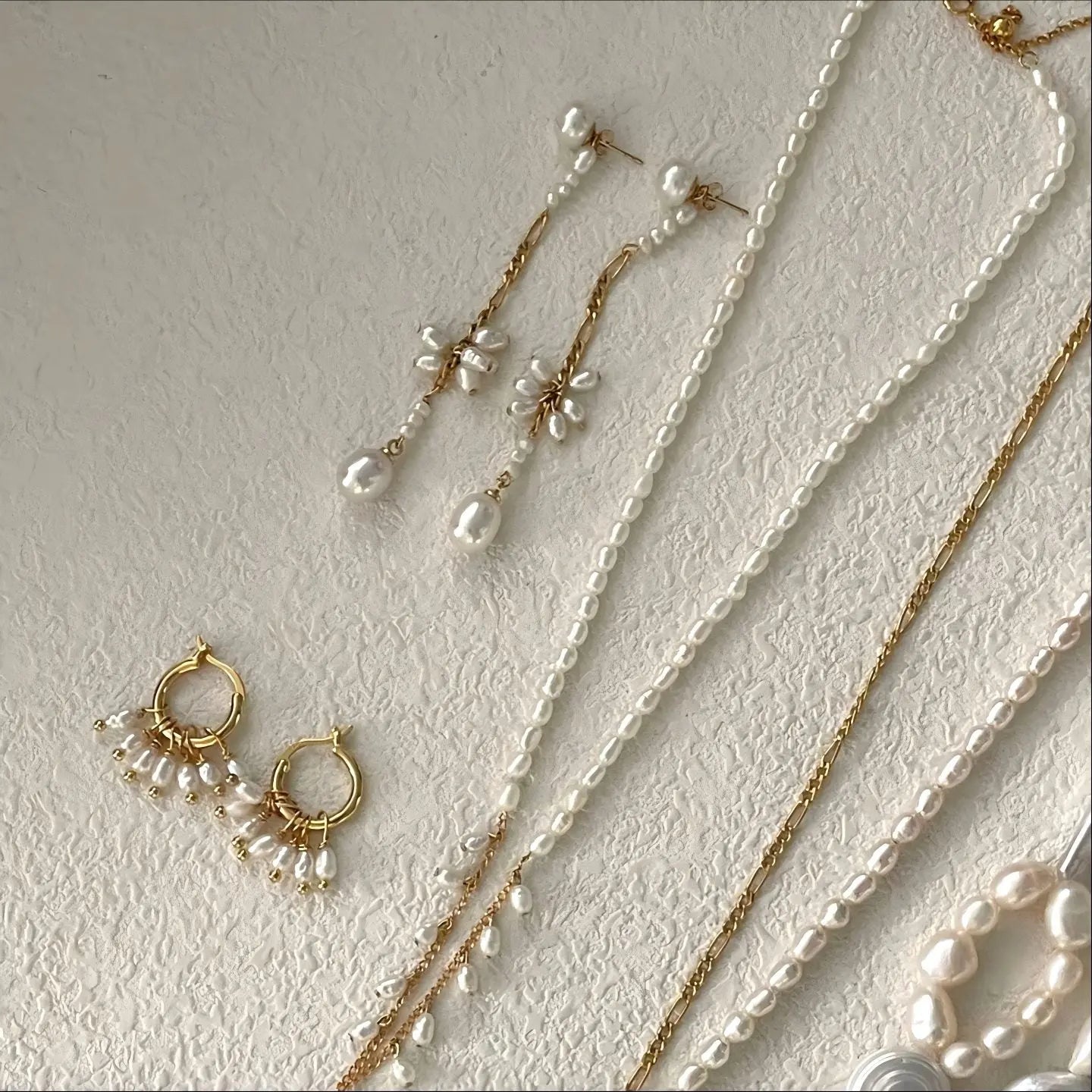 A detailed macro shot focusing on the center section of the Pearltide earring. It highlights the intricate craftsmanship of the floral cluster, hand-woven from small, oval freshwater pearls held by delicate gold wirework.