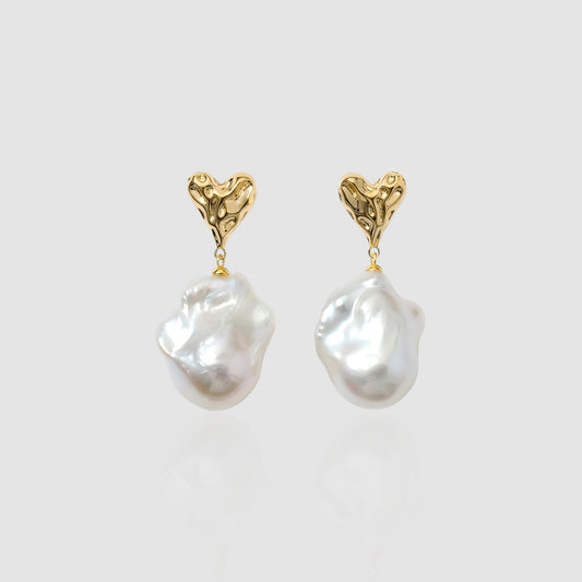 A pristine studio view showing the rich contrast between the textured 'molten' gold heart and the creamy baroque pearl drop.