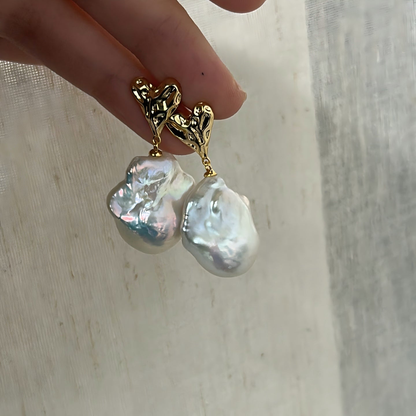 Close-up on the intricate 'crushed gold' texture of the heart stud, paired with the unique natural surface of the baroque pearl.