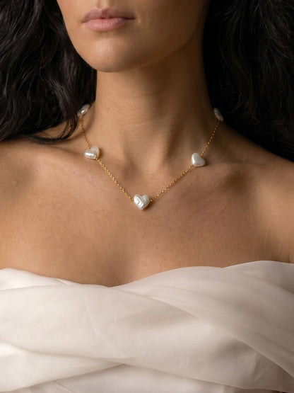 Model wearing the Pearltide Amara heart pearl station necklace, showcasing a romantic bridal look with heart-shaped baroque pearls and 14K gold-filled accents.