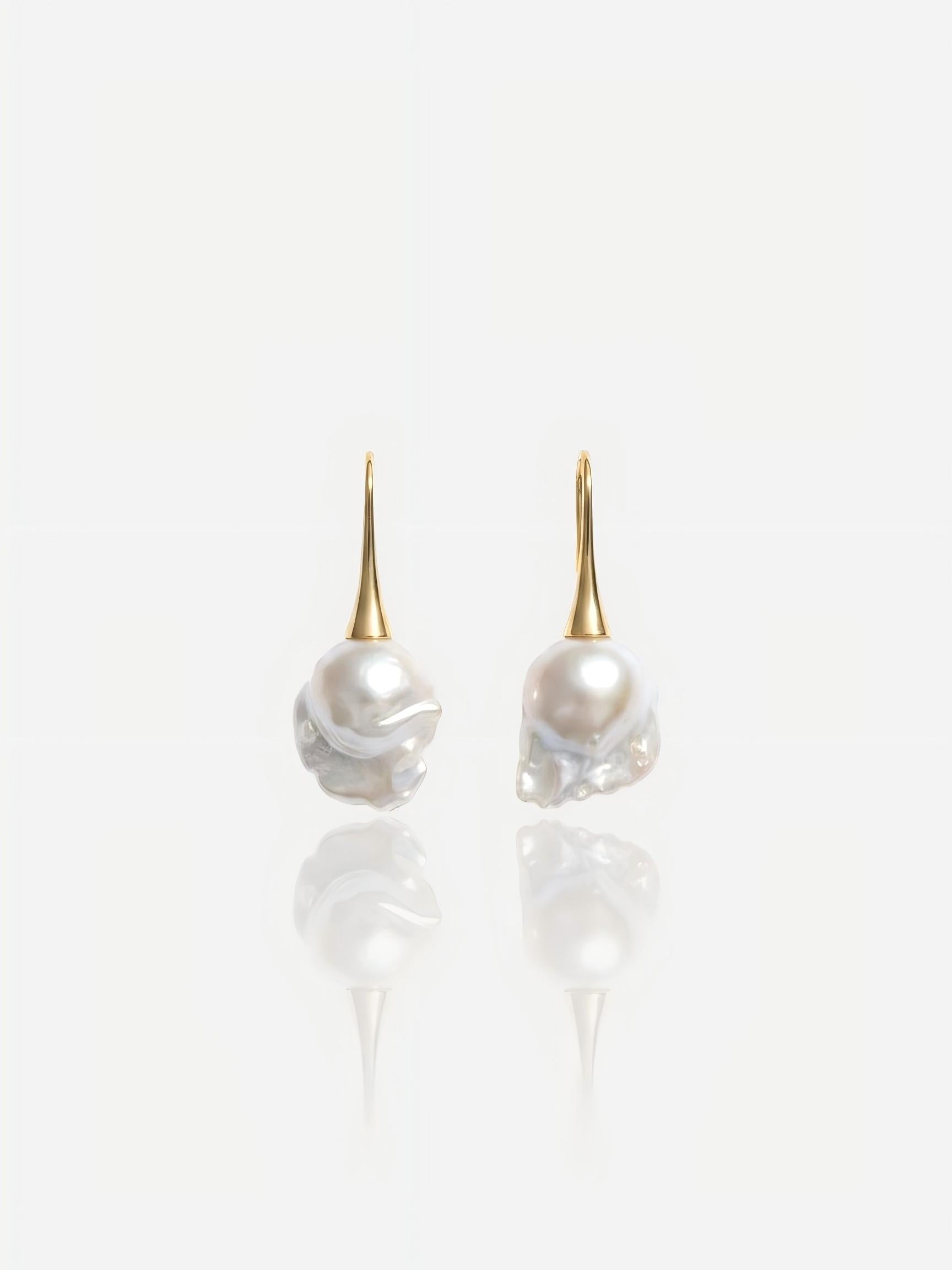 Close-up of Pearltide Aurelia baroque pearl jewelry earrings featuring sleek 14K gold-filled tapered hooks and massive lustrous organic pearls on a white reflective background, perfect for a modern bridal or resort luxury look.