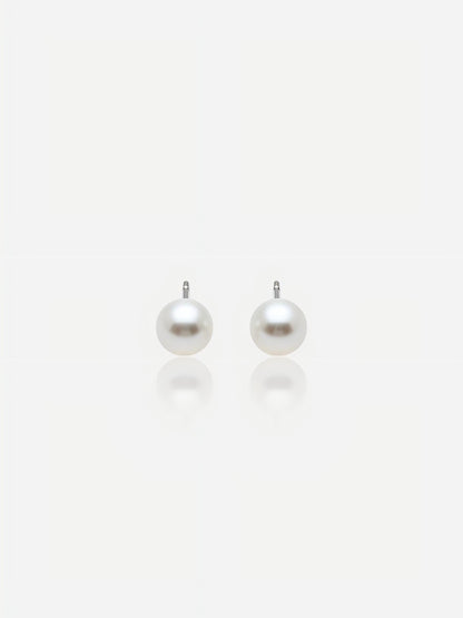 Close-up of Pearltide Aurora flawless round pearl jewelry earrings with brilliant Akoya-like mirror luster and S925 sterling silver settings on a white background with soft reflections, elegant minimalist bridal jewelry.