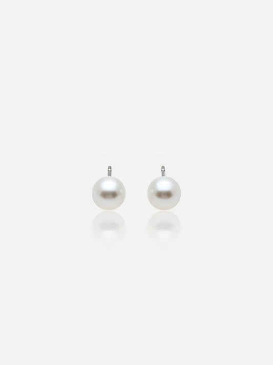 Close-up of Pearltide Aurora flawless round pearl jewelry earrings with brilliant Akoya-like mirror luster and S925 sterling silver settings on a white background with soft reflections, elegant minimalist bridal jewelry.