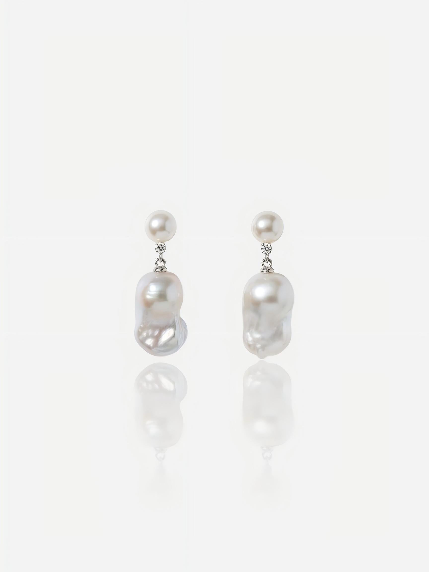 Close-up of Pearltide Celeste petite baroque pearl jewelry earrings featuring small round pearl studs, brilliant cubic zirconia links, and dainty organic drops on a white reflective background, elegant minimalist pearl jewelry.