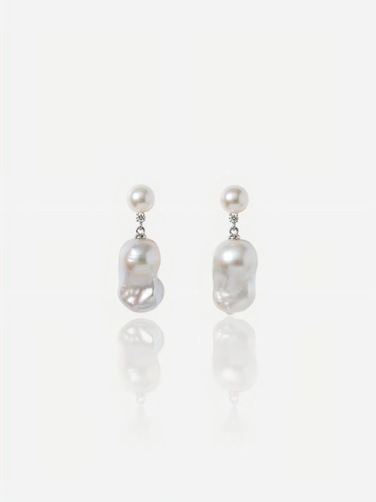 Close-up of Pearltide Celeste petite baroque pearl jewelry earrings featuring small round pearl studs, brilliant cubic zirconia links, and dainty organic drops on a white reflective background, elegant minimalist pearl jewelry.