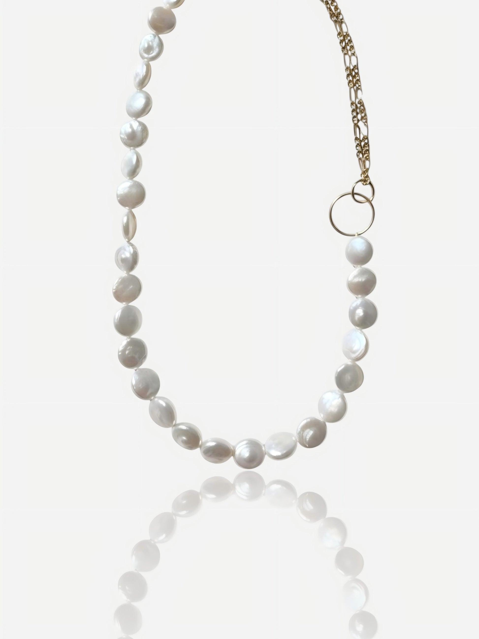 Close-up of Pearltide Eclipse necklace with half high-luster coin pearls and half 14K gold-filled chain connected by a gold ring on a white background, minimalist modernist jewelry.