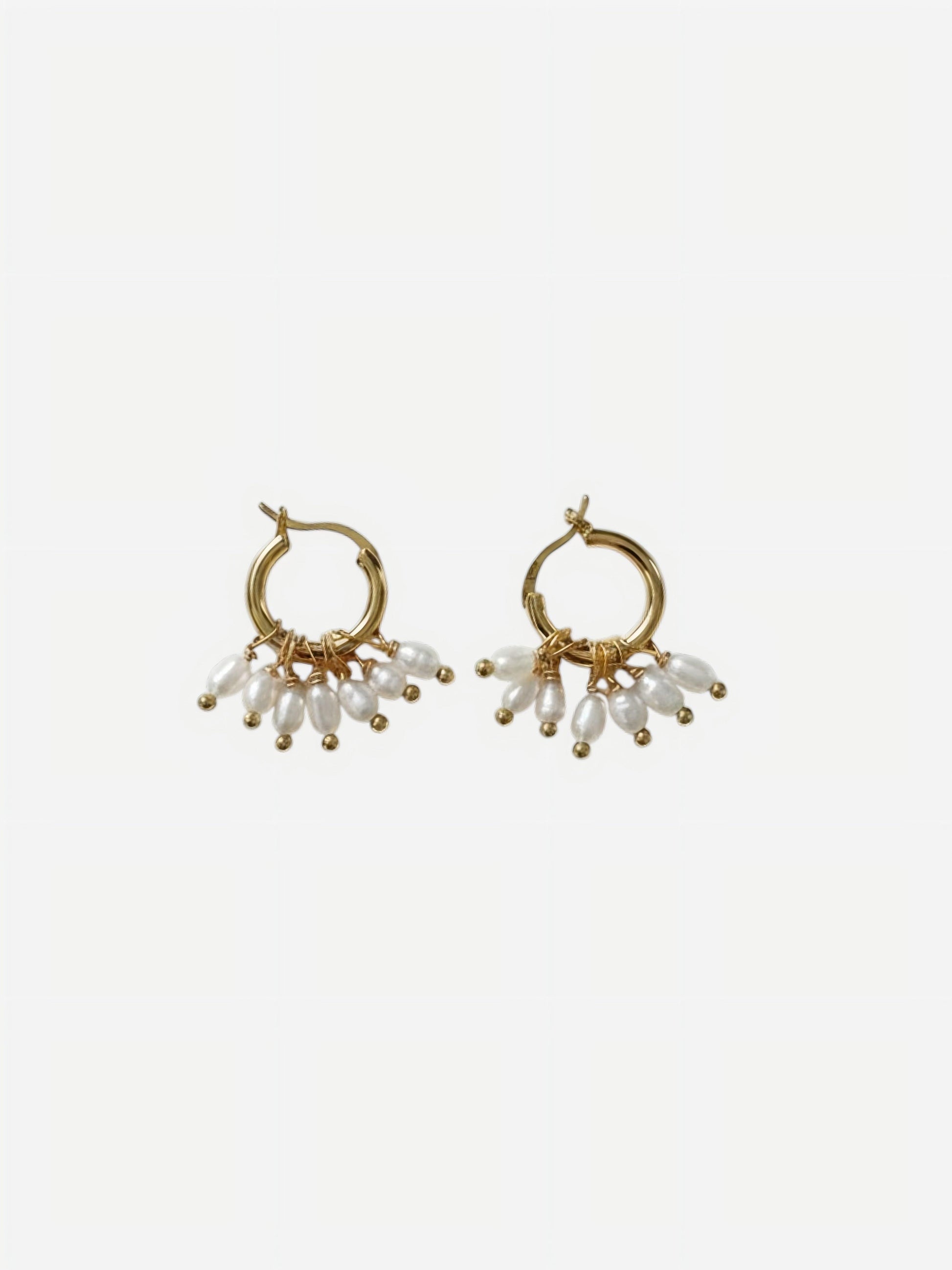 A pair of high-luster, elongated rippled baroque pearl drop earrings suspended from delicate 14K gold-filled hooks against a clean white background. Showcasing minimalist sculptural wedding jewelry.