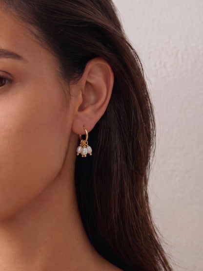 Model with glowing tan skin wearing Pearltide's elongated rippled baroque pearl drop earring in 14K gold-filled. Close-up profile view showcasing elegant, lightweight bridal jewelry and clean girl aesthetic.