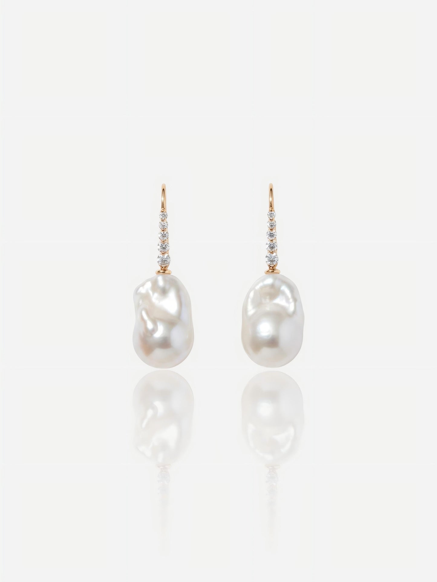 Close-up of Pearltide Elara sculptural gold pearl jewelry earrings featuring textured molten 18K gold plates and flawless round pearls on a white reflective background, elegant quiet luxury jewelry.