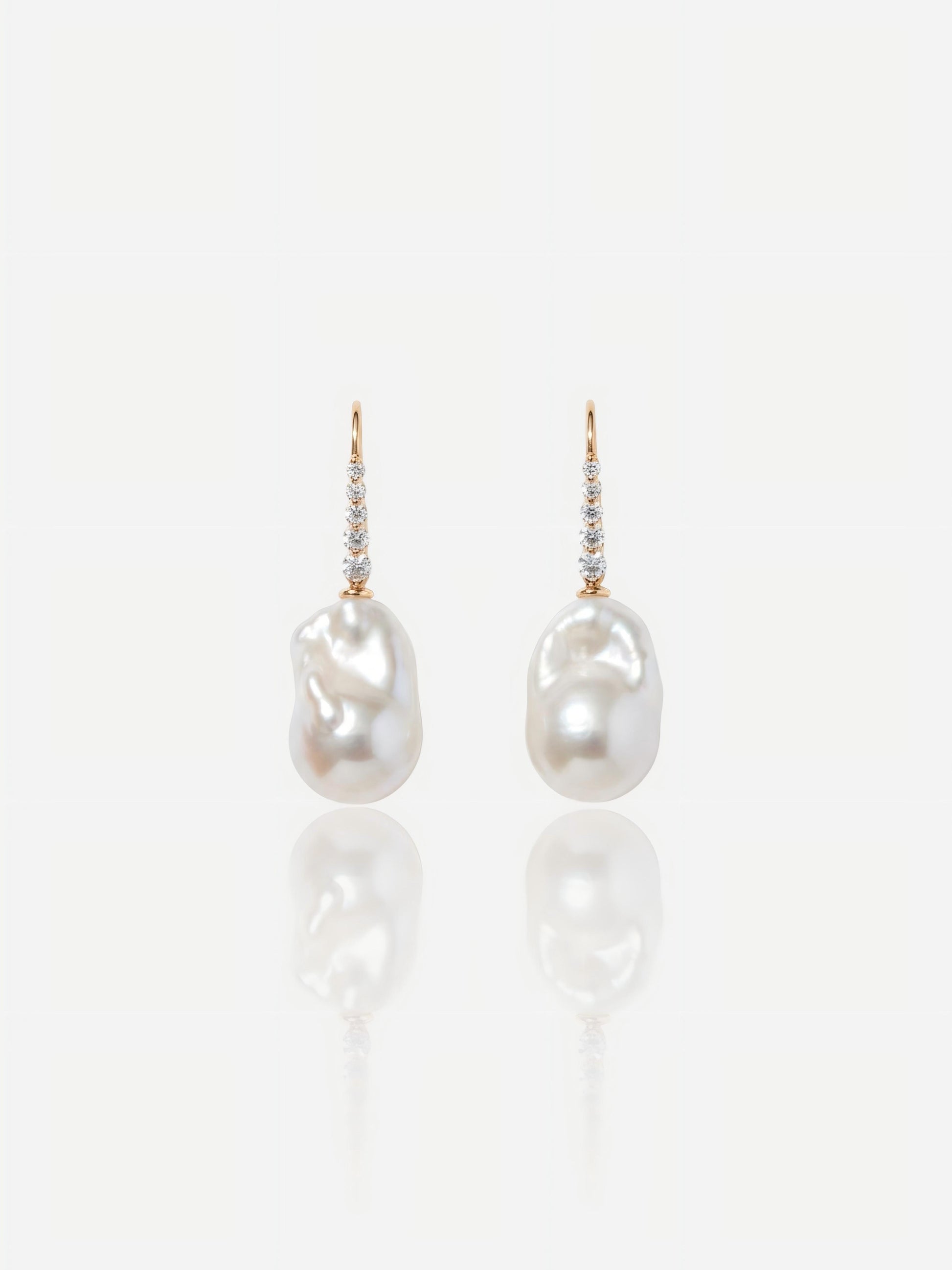 Close-up of Pearltide Elara sculptural gold pearl jewelry earrings featuring textured molten 18K gold plates and flawless round pearls on a white reflective background, elegant quiet luxury jewelry.