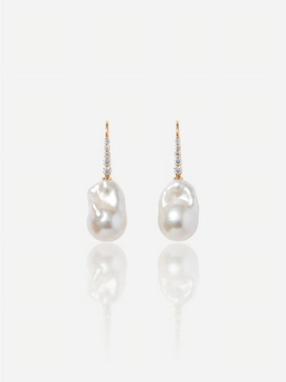 Close-up of Pearltide Elara sculptural gold pearl jewelry earrings featuring textured molten 18K gold plates and flawless round pearls on a white reflective background, elegant quiet luxury jewelry.