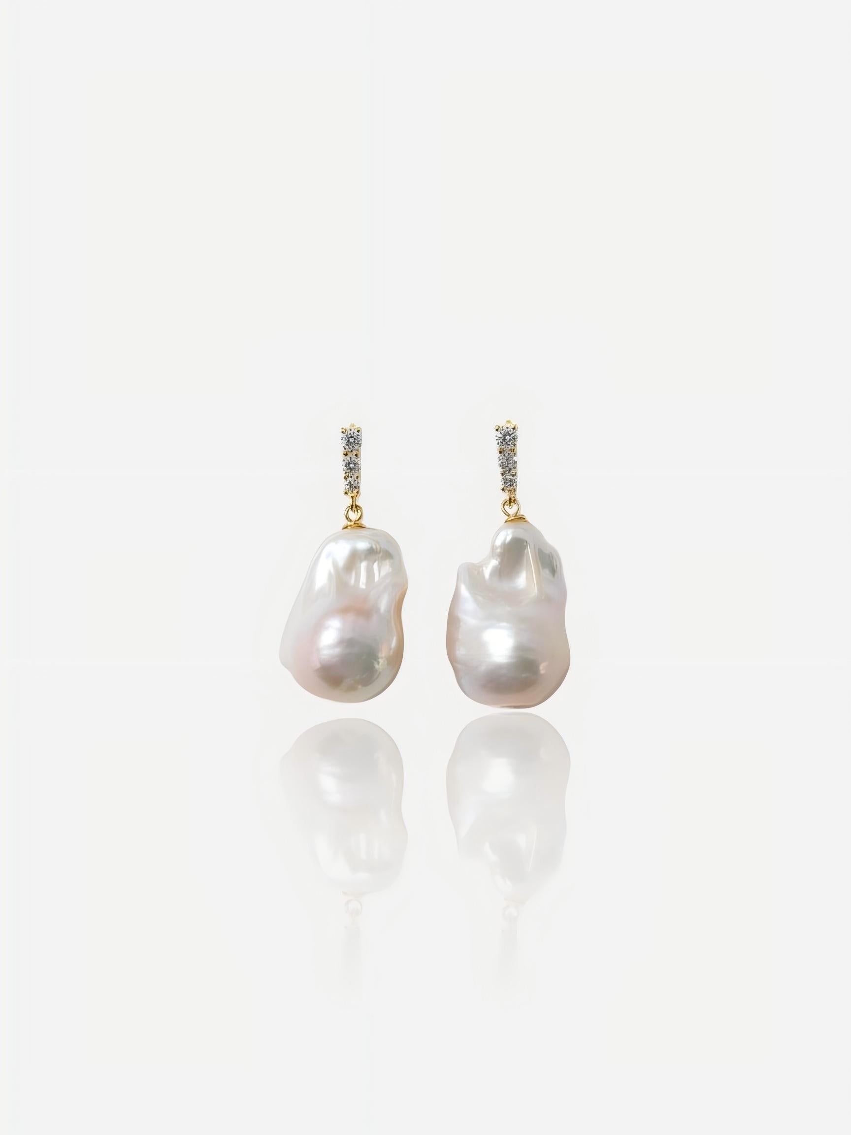 Close-up of Pearltide Elysian Rose baroque pearl jewelry earrings featuring sparkling cubic zirconia pavé bars and massive organic pearls with an iridescent rose luster on a white reflective background, elegant modern bridal jewelry.