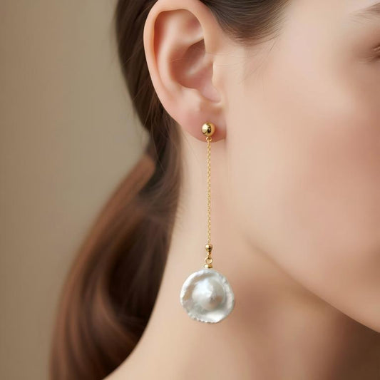 Close-up of a model wearing a single gold chain drop earring with a freshwater baroque pearl, showcasing how the earring looks when worn.