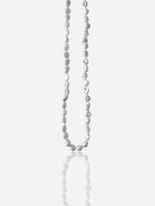 Macro close-up of Pearltide "Blue Blood" crushed silver Keshi pearl necklace with icy metallic luster on an S925 sterling silver chain, minimalist organic resort jewelry for a modern sun-kissed look.