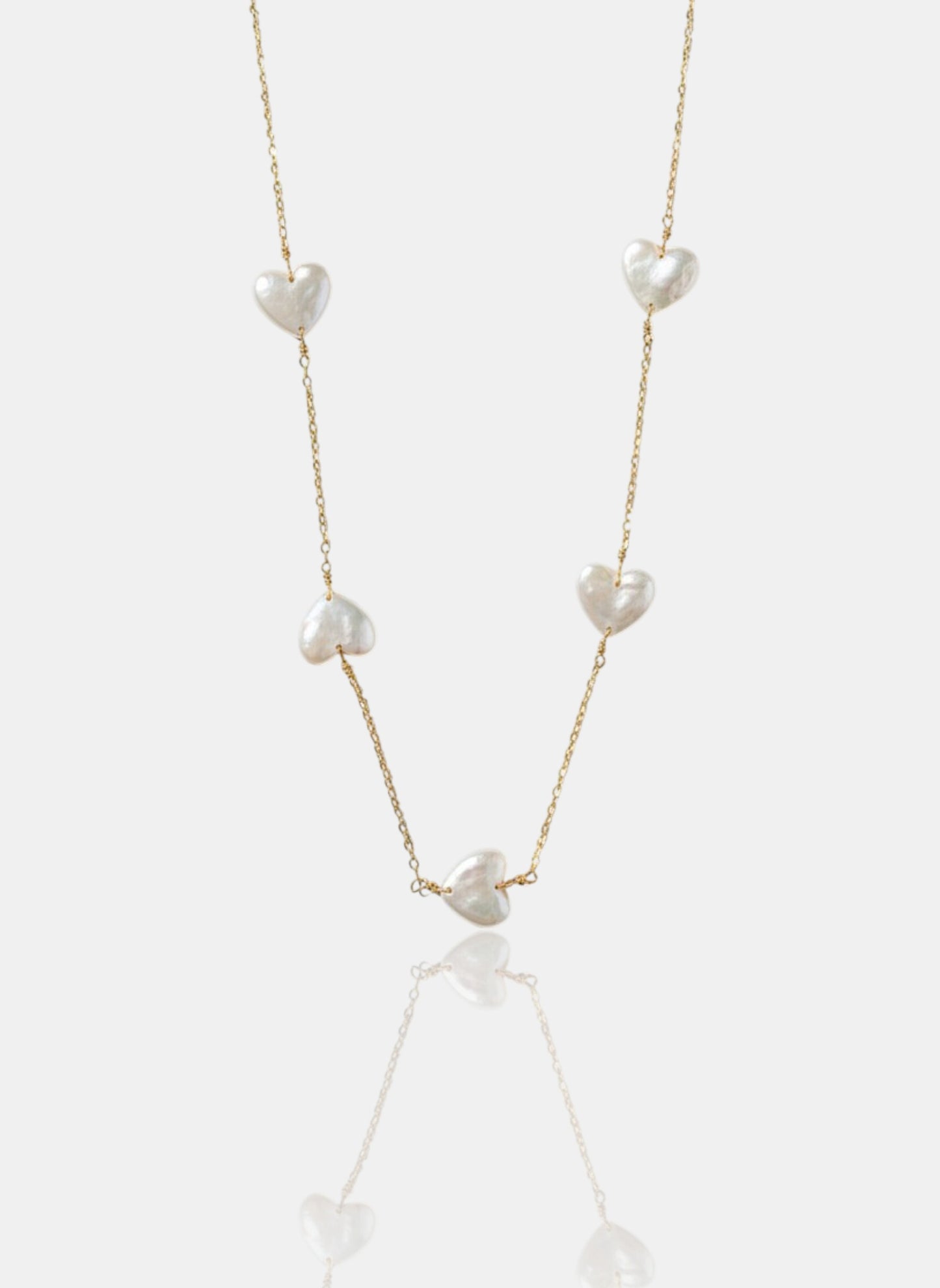 Close-up of Pearltide Amara station necklace with five heart-shaped pearls on a 14K gold-filled chain against a white background, minimalist romantic jewelry.