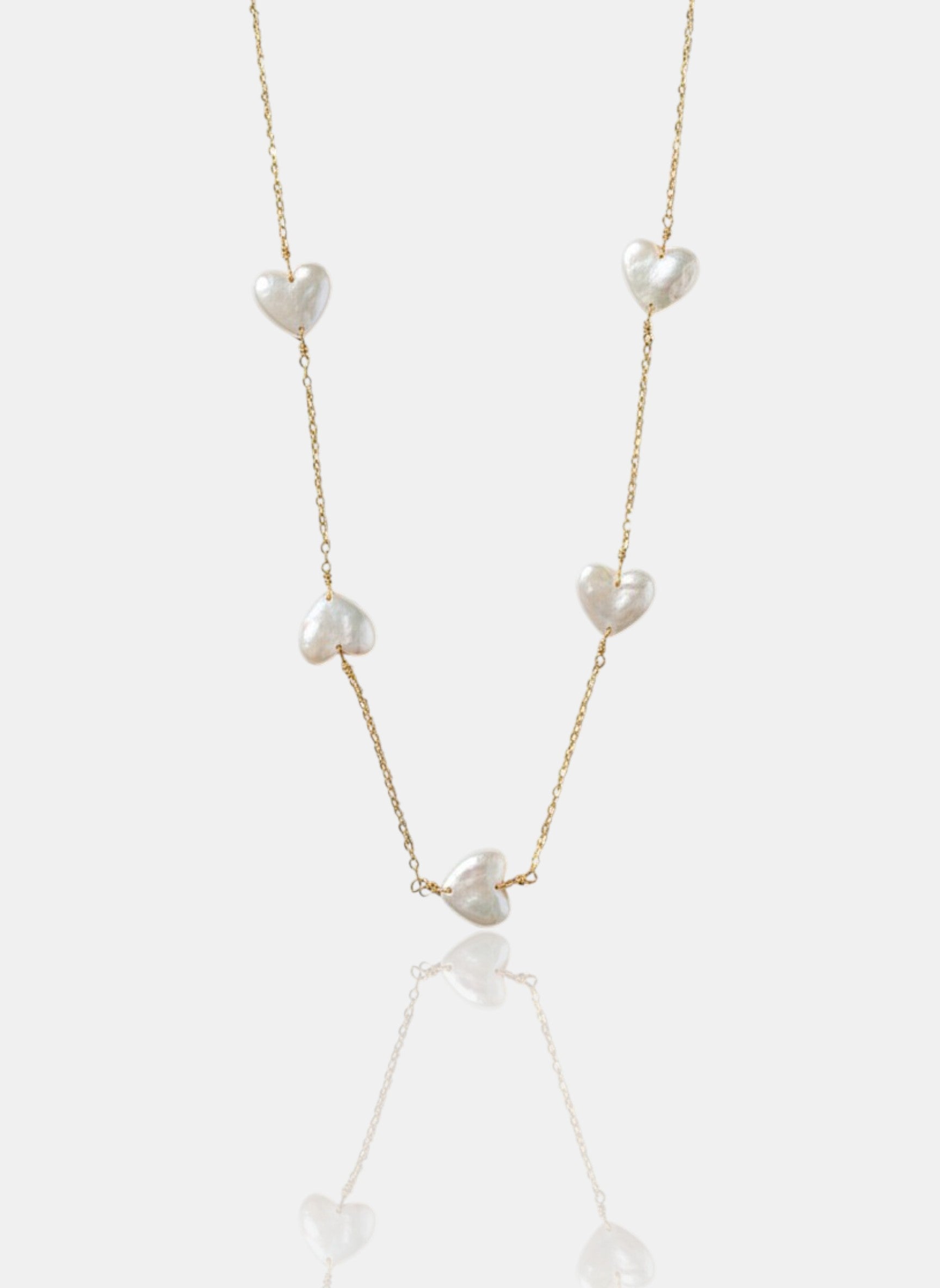 Close-up of Pearltide Amara station necklace with five heart-shaped pearls on a 14K gold-filled chain against a white background, minimalist romantic jewelry.