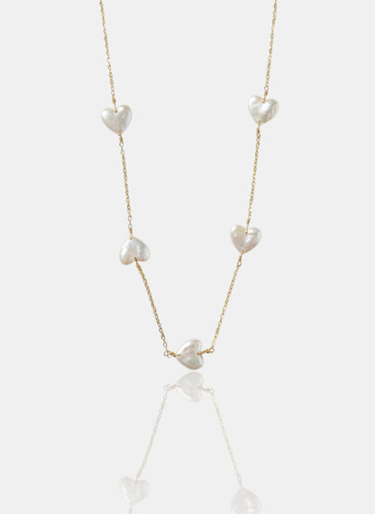 Close-up of Pearltide Amara station necklace with five heart-shaped pearls on a 14K gold-filled chain against a white background, minimalist romantic jewelry.