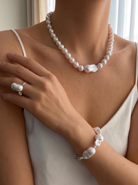 Model with tan skin wearing the Pearltide Serene Focal necklace, showcasing a modern bridal look with a large baroque pearl centerpiece and S925 sterling silver accents.