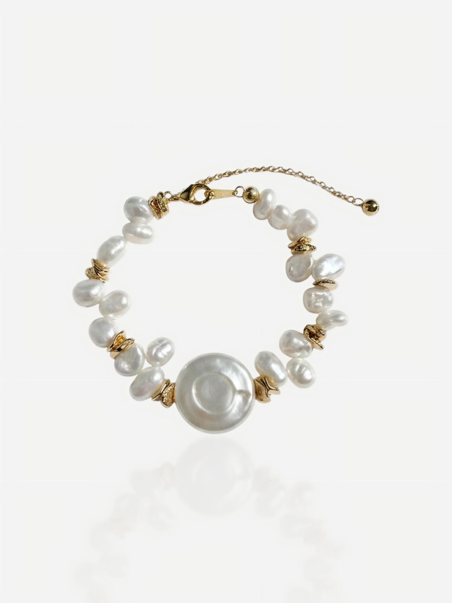 Close-up of Pearltide Solaris bracelet featuring a large central coin pearl and irregular baroque pearls with 18K gold-plated sterling silver accents on a white background, minimalist resort jewelry.