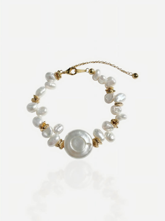 Close-up of Pearltide Solaris bracelet featuring a large central coin pearl and irregular baroque pearls with 18K gold-plated sterling silver accents on a white background, minimalist resort jewelry.