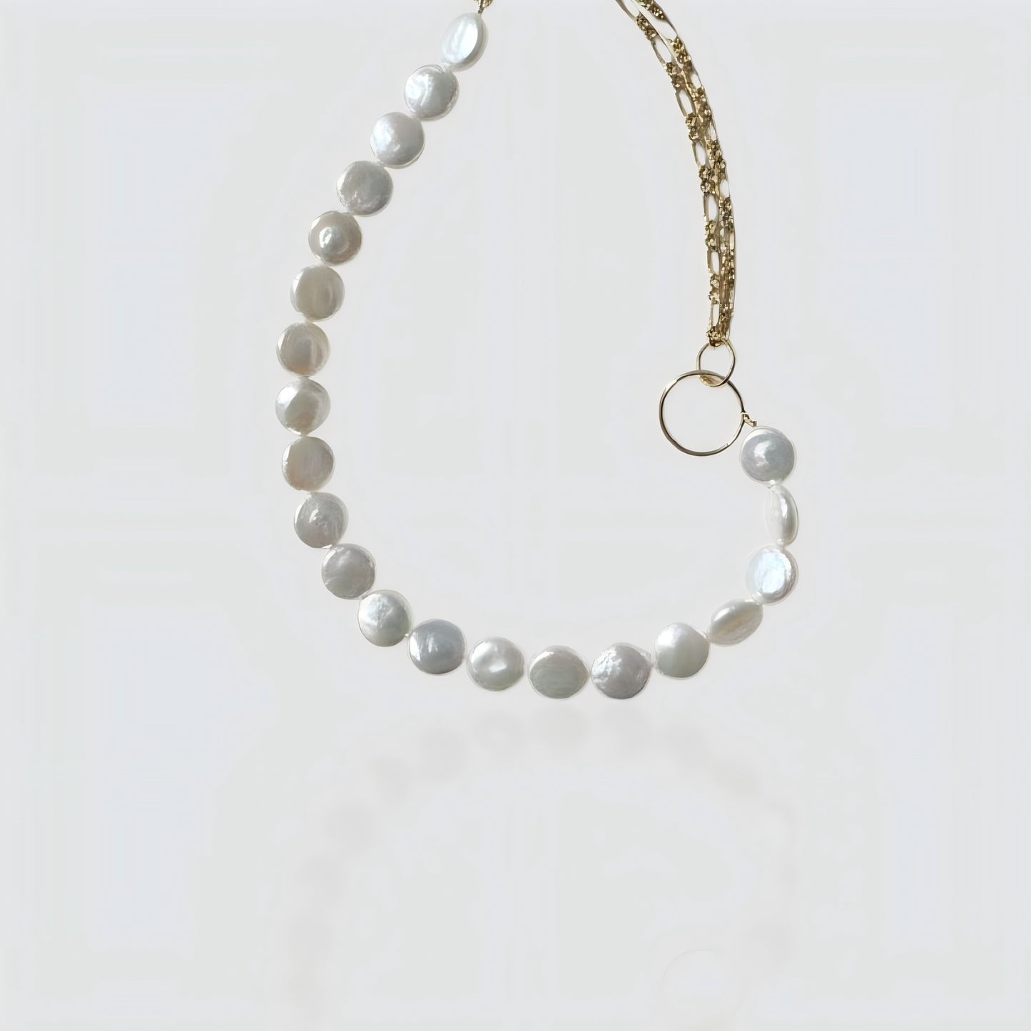 Studio shot of a half-pearl, half-chain necklace featuring flat coin pearls and a gold link chain connected by a ring.