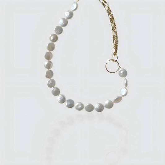 Studio shot of a half-pearl, half-chain necklace featuring flat coin pearls and a gold link chain connected by a ring.