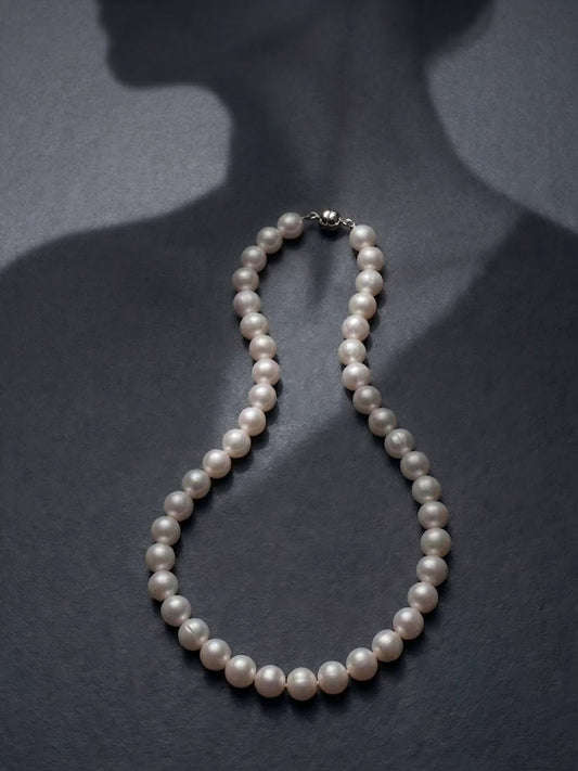 Classic round pearl necklace showcased on a dark silhouette, emphasizing a timeless, Old Money aesthetic.