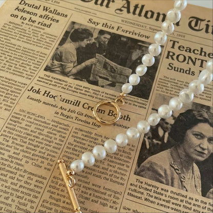 Macro shot showing the texture of natural freshwater pearls and the polished finish of the gold T-bar toggle clasp.