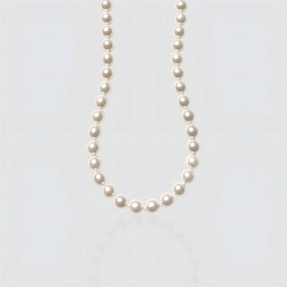 Studio shot of a large, metallic-luster Edison baroque pearl necklace on a neutral grey background.