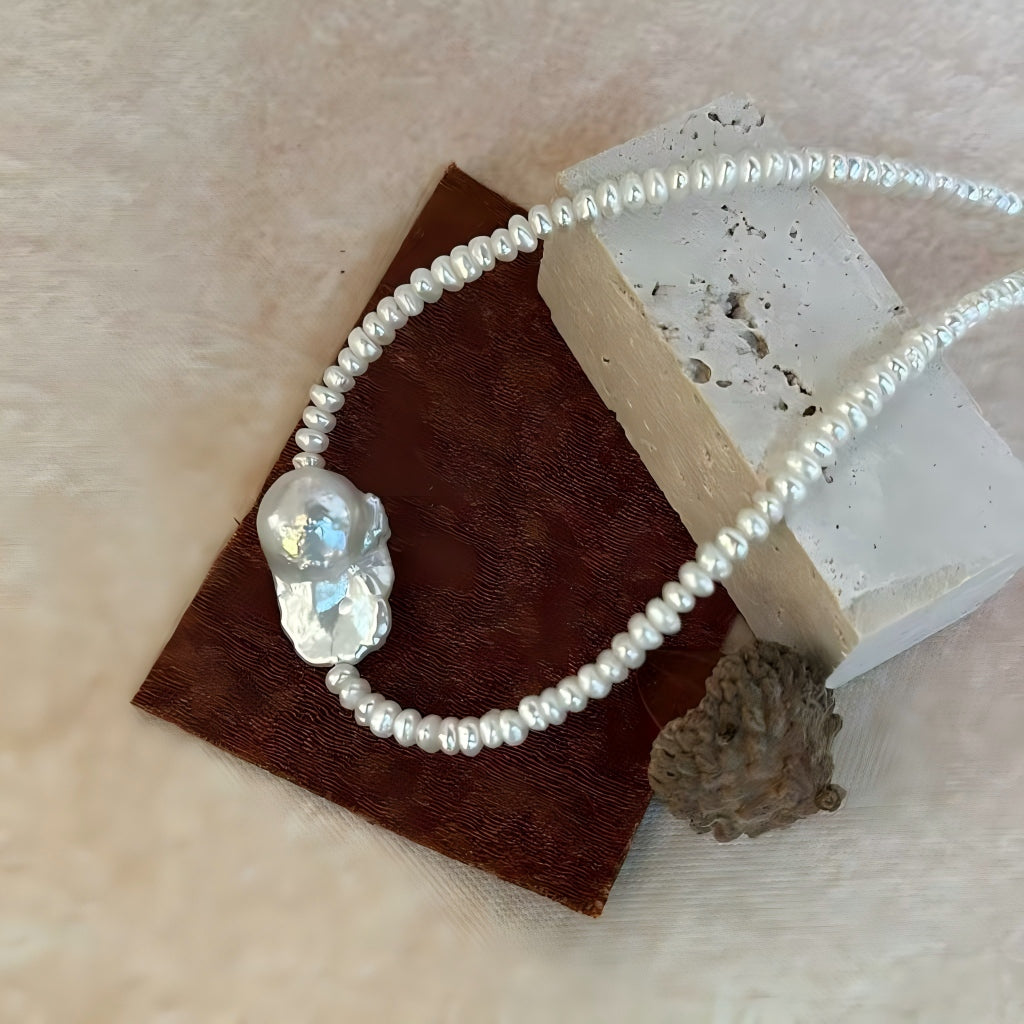 Macro detail shot of the large baroque pearl pendant showing natural growth texture, high luster, and iridescent surface.