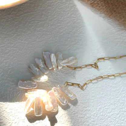A close-up view showing the irregular texture and rainbow luster of the stick pearls and their connection to the gold paperclip chain links.