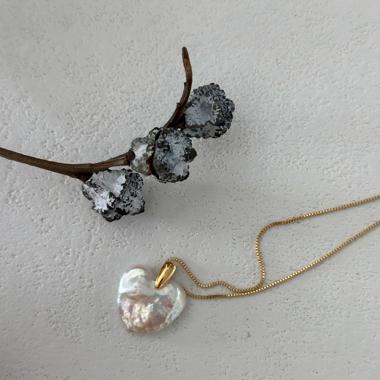 Close-up showing the thick, puffed dimension of the baroque pearl heart and the polished finish of the gold bail.