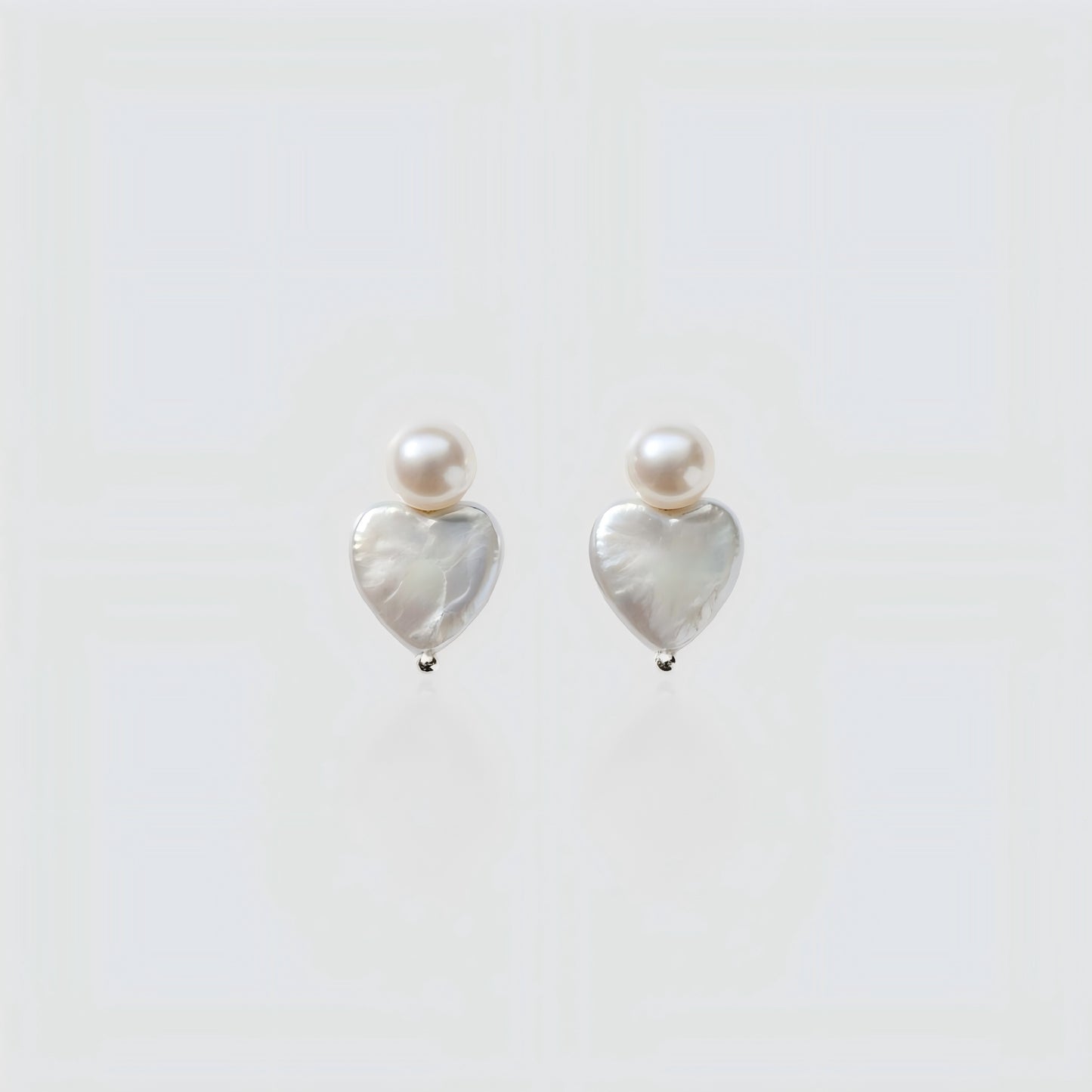 Pure Elegance. A detailed view of the Pearltide Heart Pearl Studs against a pristine background, highlighting the organic texture and creamy luster of the baroque pearls.