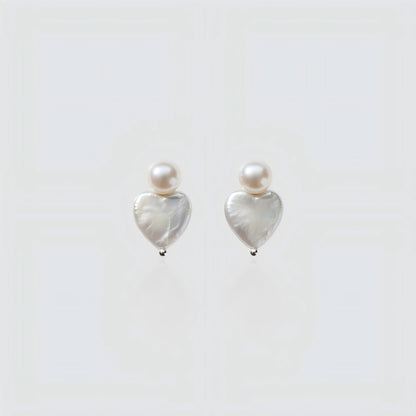 Pure Elegance. A detailed view of the Pearltide Heart Pearl Studs against a pristine background, highlighting the organic texture and creamy luster of the baroque pearls.