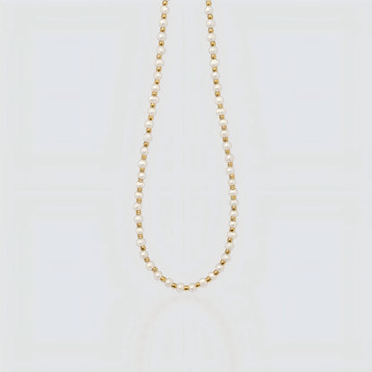Studio product shot of a delicate necklace featuring alternating small white freshwater pearls and gold beads on a light grey background.