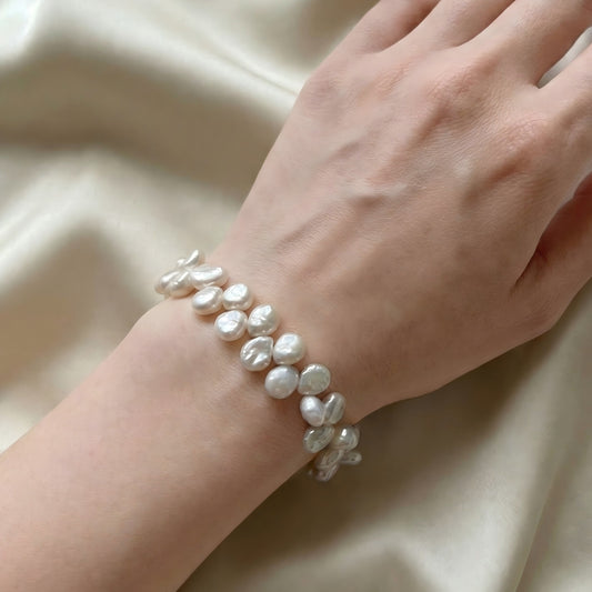 Woman wearing a textured double-row baroque pearl bracelet, styled with a modern minimalist outfit to highlight the organic pearl shapes.