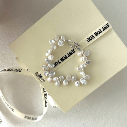 Close-up detail of irregular freshwater pearls woven into a cluster formation, showing the silver clasp and high-luster surface texture.