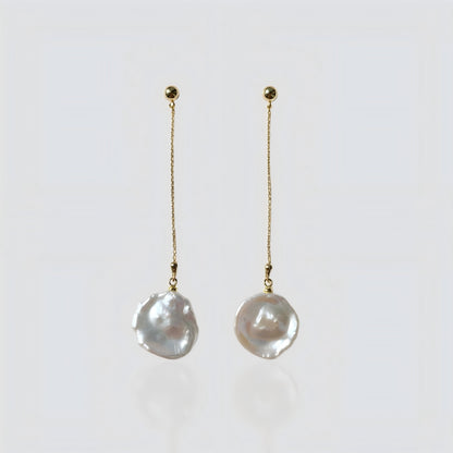 A pair of elegant gold chain drop earrings with irregular freshwater baroque pearls, presented on a soft grey background for clear product viewing.