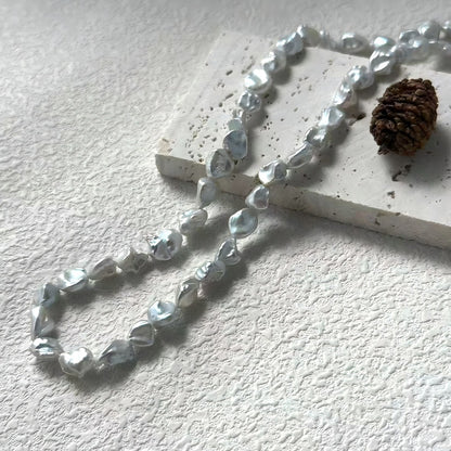 A stylish woman wearing the metallic silver-grey pearl necklace with a black top, highlighting the cool tones of the pearls.