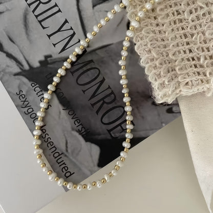 Extreme close-up of the necklace showing the high-polished gold beads connected to lustrous white freshwater pearls.