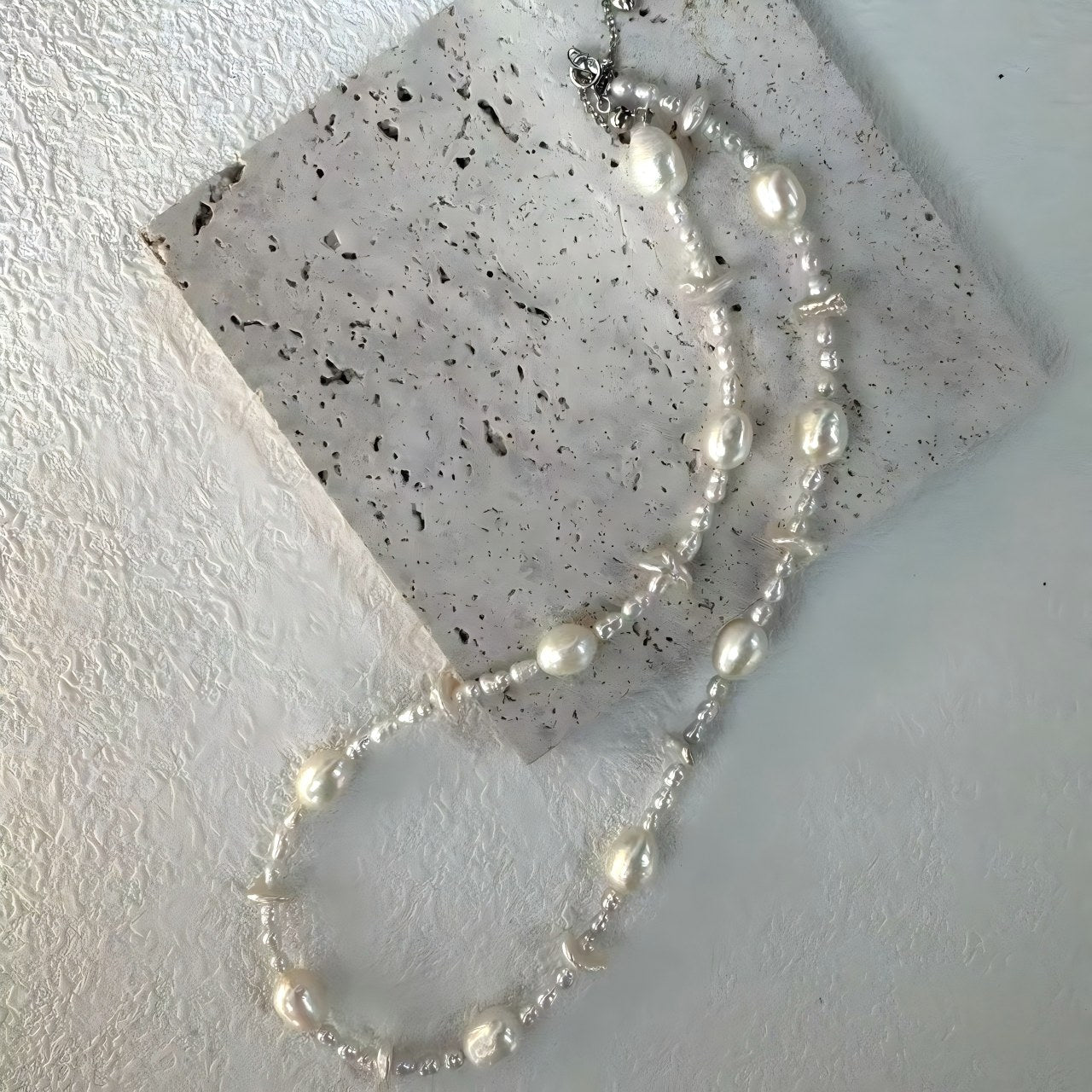 Extreme close-up showing the size contrast between the large organic pearls and the tiny spacer beads.