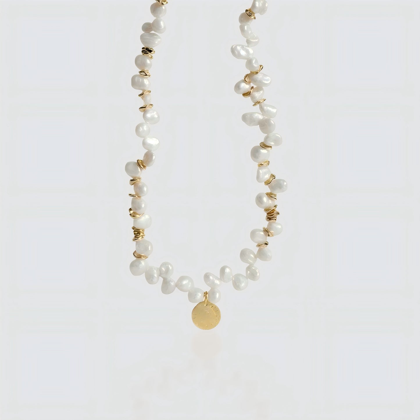 Artisanal Craftsmanship. A crisp look at the interplay between shimmering pearls and the vintage-inspired gold coin.